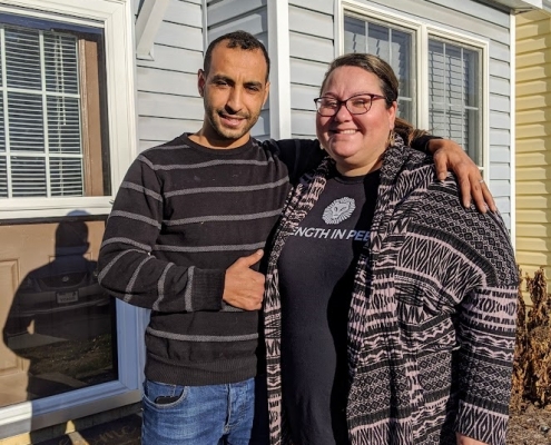 Katie and her husband standing in front of their new home in Harrisonburg