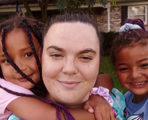FSS Graduate Amber with her two girls on either side in front of their new home.