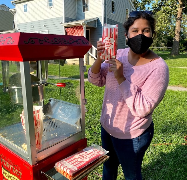 Heidi with Harrisonburg Baptist poses with a bag of popcorn next to a red popcorn machine.
