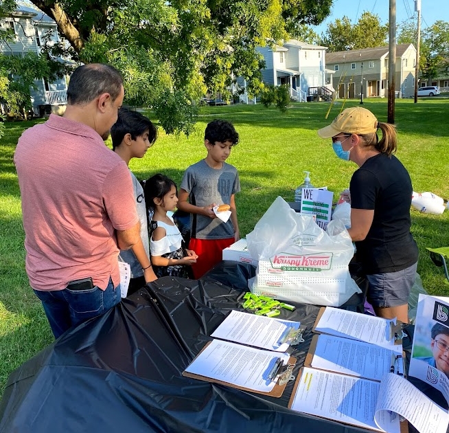 A family talks with Elizabeth from Big Brothers Big Sisters at a table.