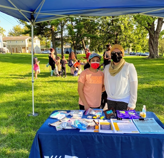 An employee with the Virginia Department of Health and a young girl stand side by side at the VDH table under a canopy. 