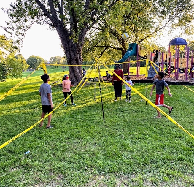 Kids stand on four corners of a 5ft high 4-square volleyball net. 